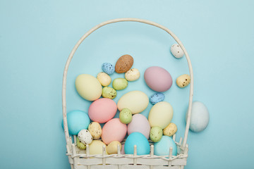 Top view of painted easter chicken and quail eggs in straw basket
