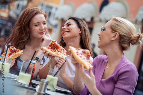 Cheerful friends eating pizza, having fun outdoors