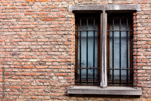 Old house with copy space on the red bricks wall. Old wooden windows with metal bars on the old brick house