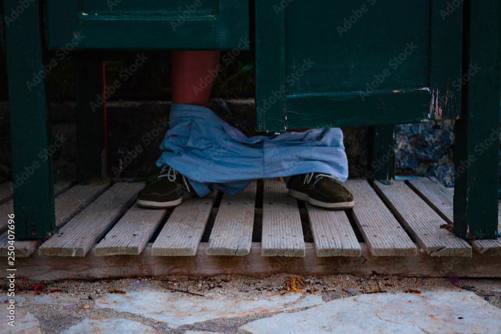 The feet of a man who sits in the toilet. Public wooden wc with wooden ...