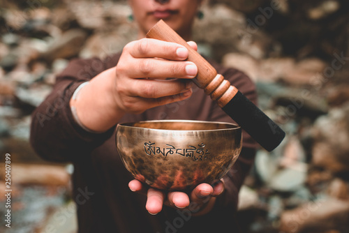woman holding and playing a singing bowl tibetan bowl