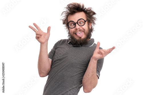 Crazy bearded Man with funny Haircut in eye Glasses making grimace - funny face. Casual Silly guy, isolated on white background. Emotions, and signs concept. photo