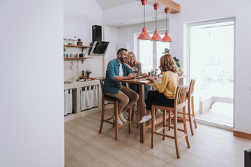 Happy family chatting and laughing while having dinner at home