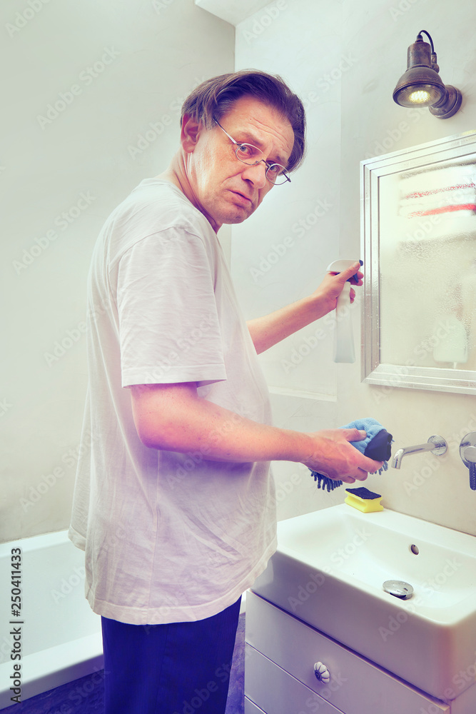 Older poor man cleaning his home with cleaner and sponge Older poor man cleaning his home with cleaner and sponge