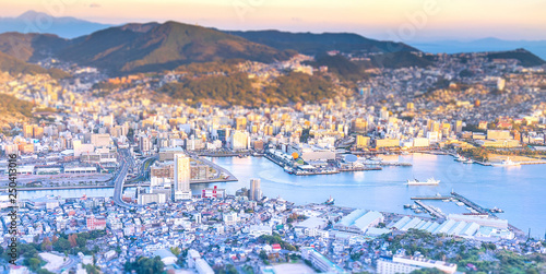 Business concept, tilt shift effect modern cityscape of nagasaki dusk from mount inasa, the new top 3 nightview of the world, aerial view, copy space photo