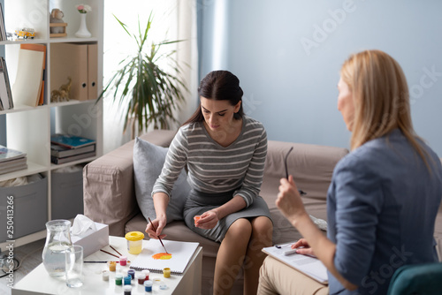 Εκτύπωση καμβά Brunette Caucasian woman is painting during art therapy session indoors