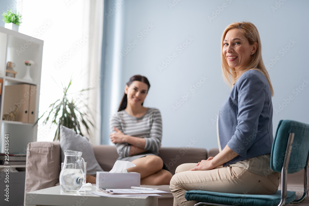 Low angle of psychologist and her patient posing for camera indoors Low angle of psychologist and her patient posing for camera indoors