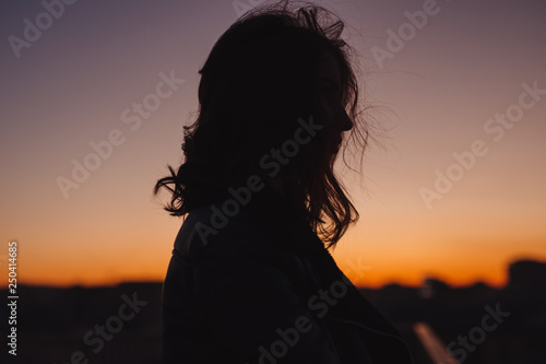 Silhouette of woman thinking about future at sunset in city