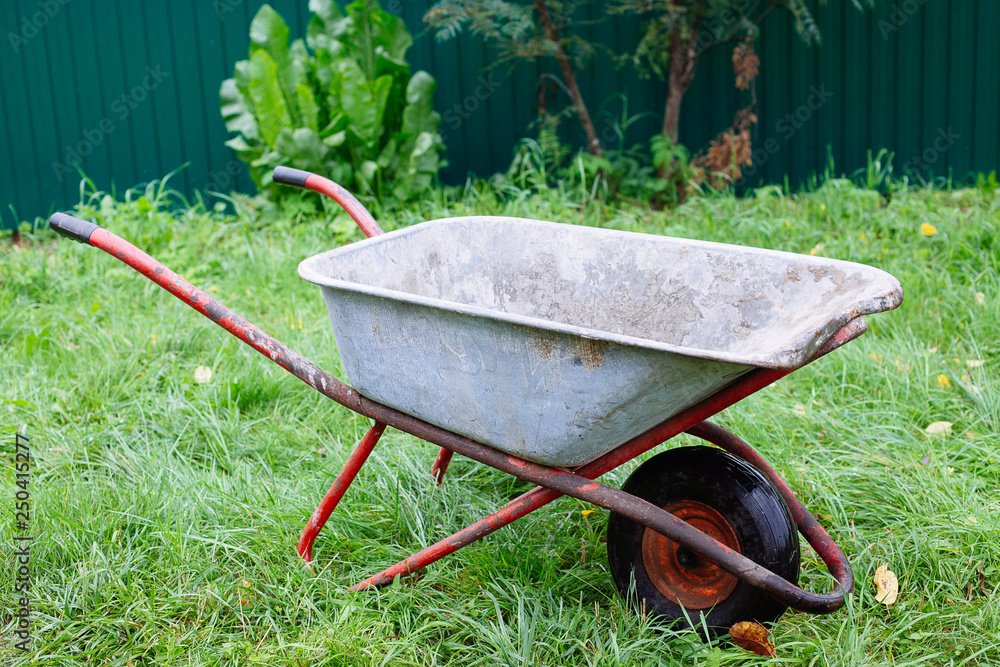 Wheelbarrow on green grass lawn in a farm garden Wheelbarrow on green grass lawn in a farm garden
