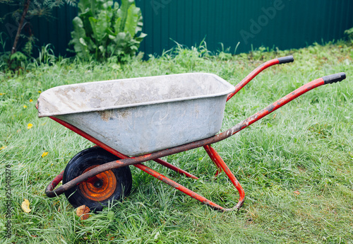 Wheelbarrow on green grass lawn in a farm garden