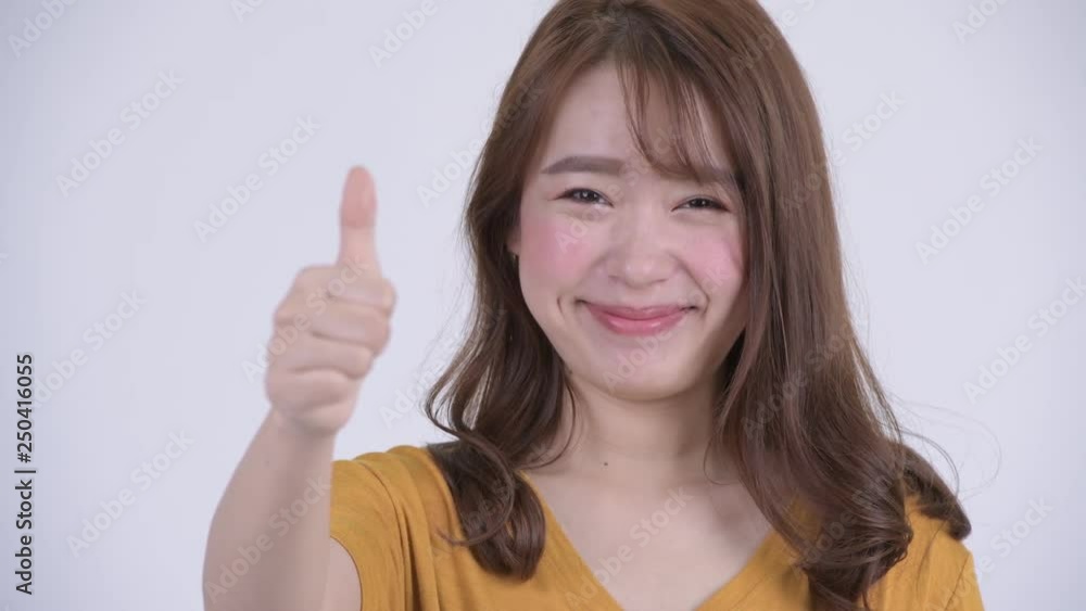 Face of happy young beautiful Asian woman giving thumbs up Face of happy young beautiful Asian woman giving thumbs up