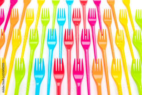 Many color plastic forks on a bright background