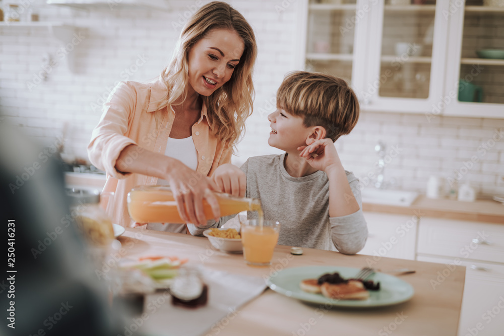 Boy looking at his mother pouring juice into his glass Boy looking at his mother pouring juice into his glass