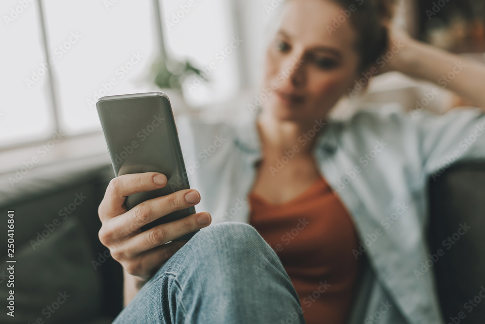 Relaxed female sitting on couch with smartphone Relaxed female sitting on couch with smartphone