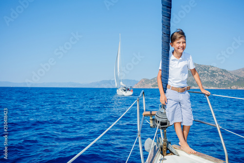 Little boy on board of sailing yacht on summer cruise. Travel adventure, yachting with child on family vacation. photo