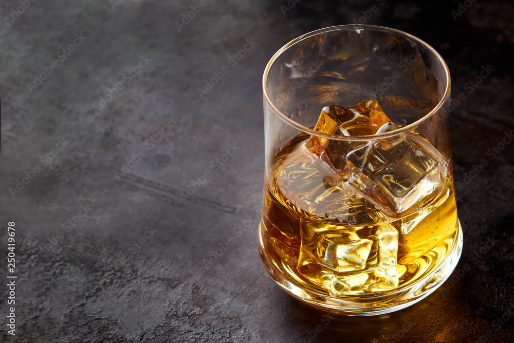 Glass of whiskey with ice cubes (on the rocks) on black background. Copy space Glass of whiskey with ice cubes (on the rocks) on black background. Copy space