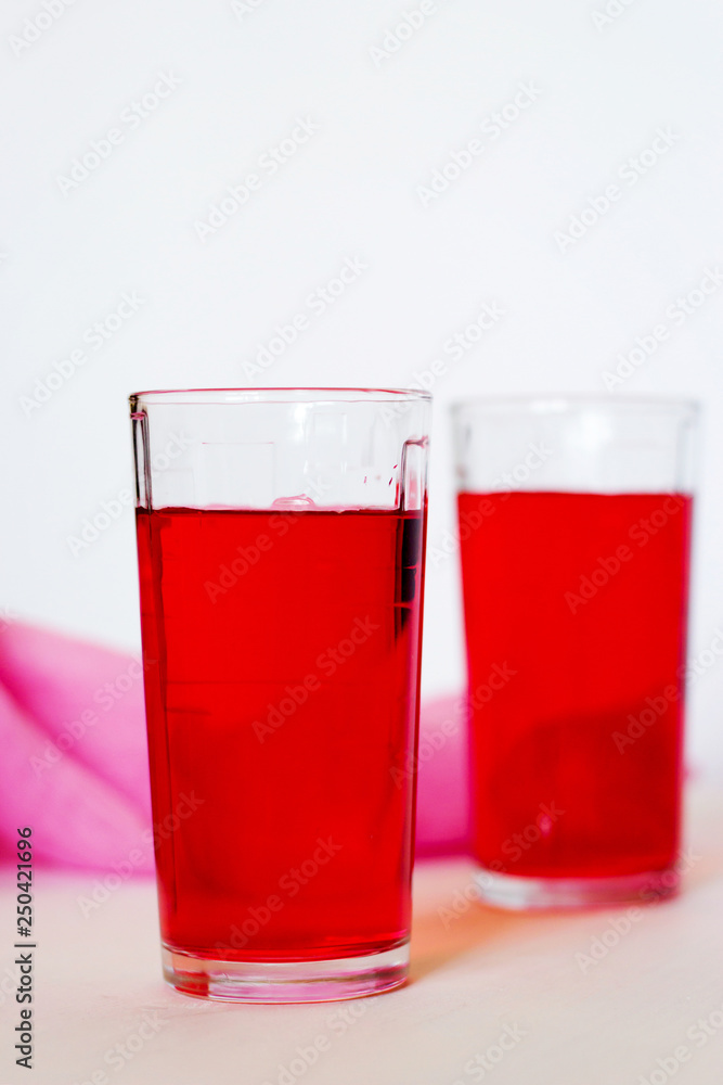 Fruit and berry red juice in glasses on a white background. Fresh and cold summer drink. Fruit and berry red juice in glasses on a white background. Fresh and cold summer drink.