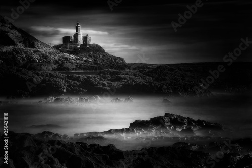 The Mumbles with it's lighthouse as seen from Bracelet Bay on the Gower Peninsular Wales, UK black & white monochrome image