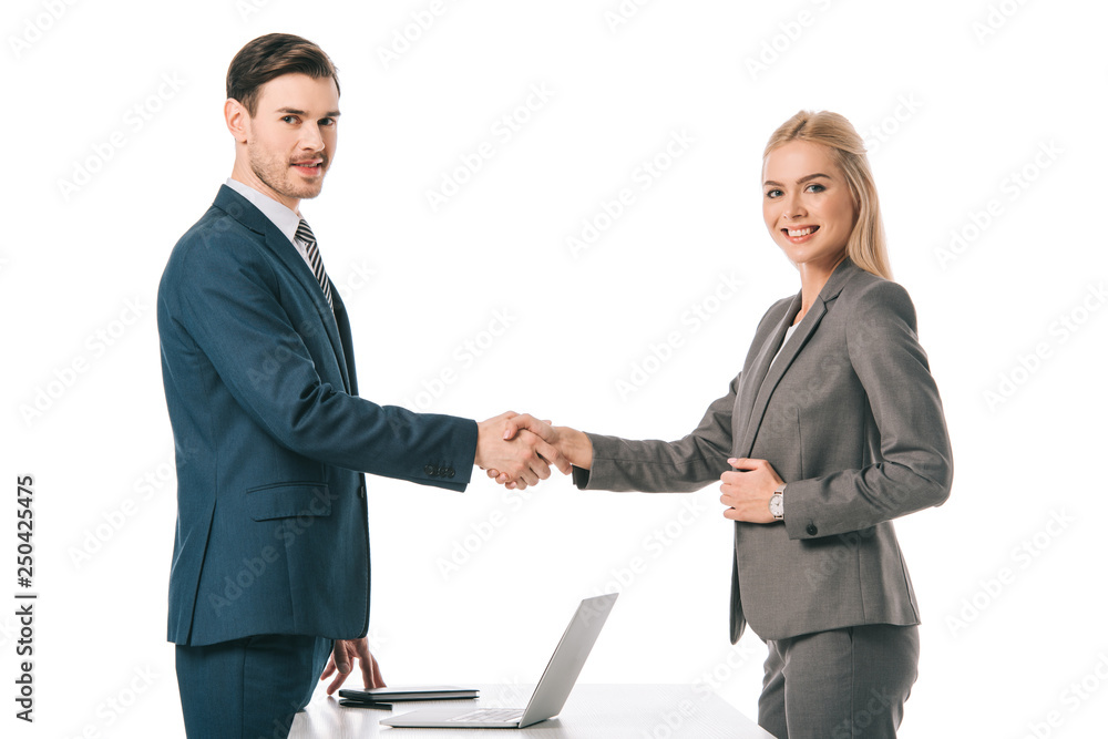 successful businesspeople shaking hands and having deal at workplace with laptop, isolated on white