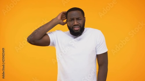 Young african american man shrugging in confusion, isolated on yellow background