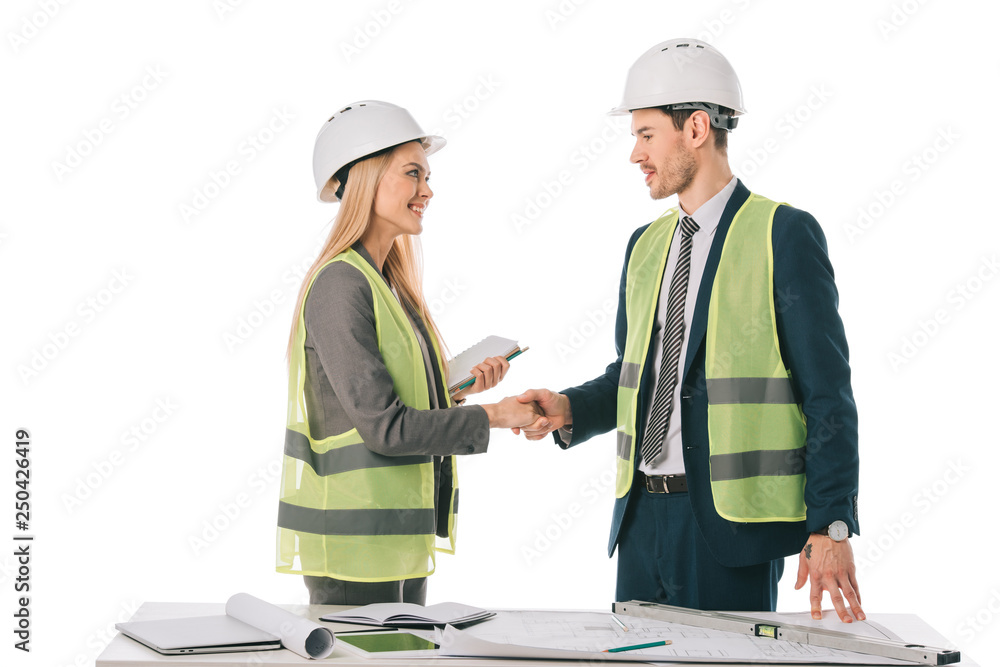 architects in safety vests and hardhats making deal and shaking hands, isolated on white architects in safety vests and hardhats making deal and shaking hands, isolated on white