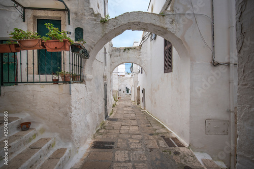 A street view of the old town - province of Brindisi, region of Apulia. Picturesque narrow with traditional white washed houses in the old historic center of Ostuni, Puglia, Italy © mitzo_bs