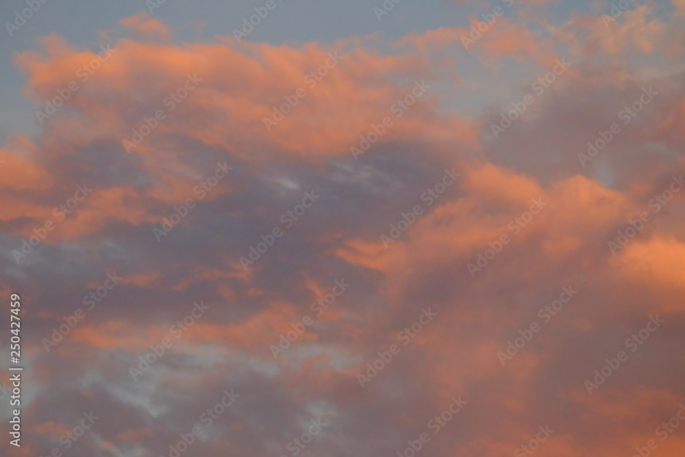 Orange clouds at dusk on grey sky for background texture 