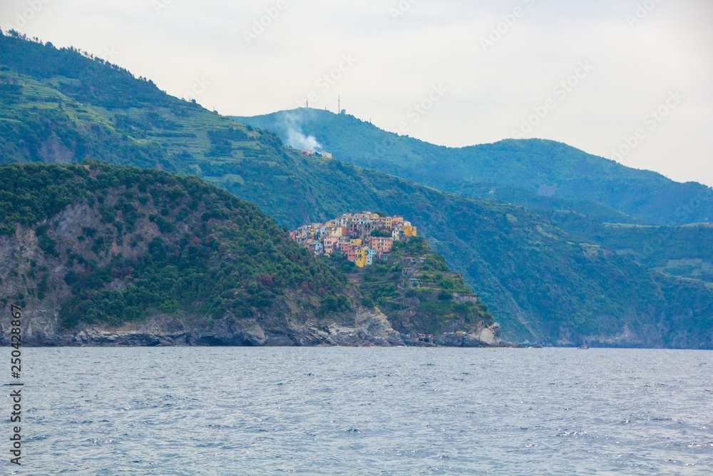 The town of Corniglia, one of the five small towns in the Cinque Terre national Park, Italy. View from the excursion ship. Amazing colorful small town located in the mountains near the sea. The town of Corniglia, one of the five small towns in the Cinque Terre national Park, Italy. View from the excursion ship. Amazing colorful small town located in the mountains near the sea.
