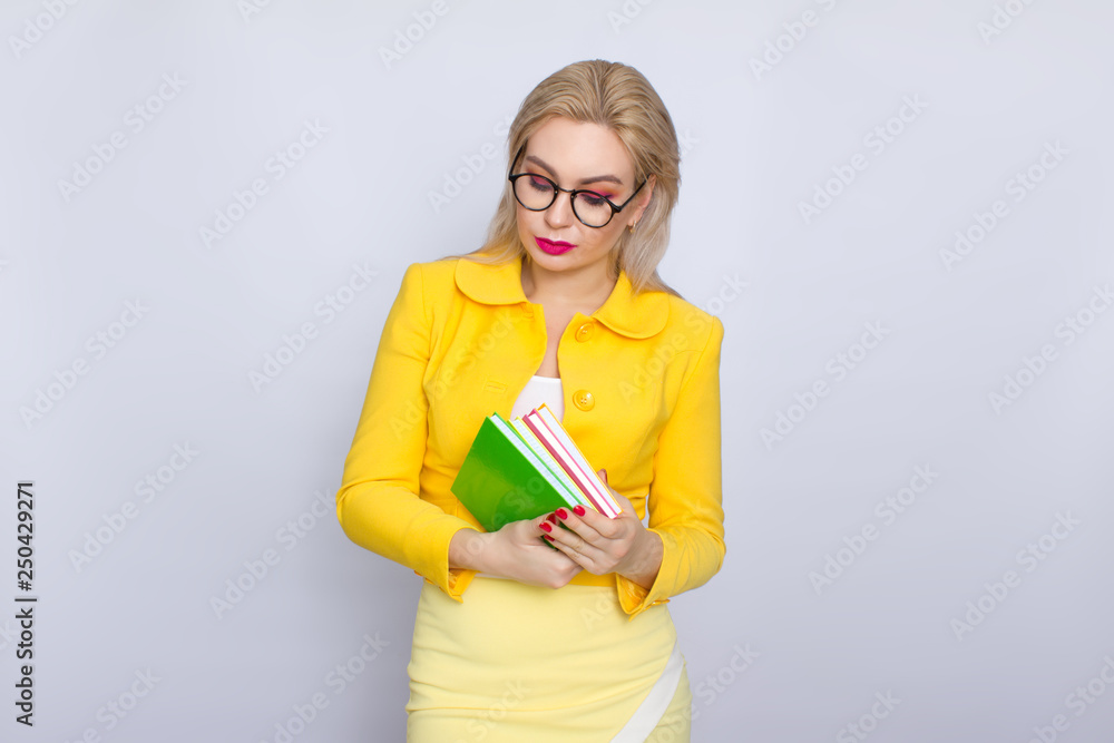 Woman in yellow suit holding books in her hands