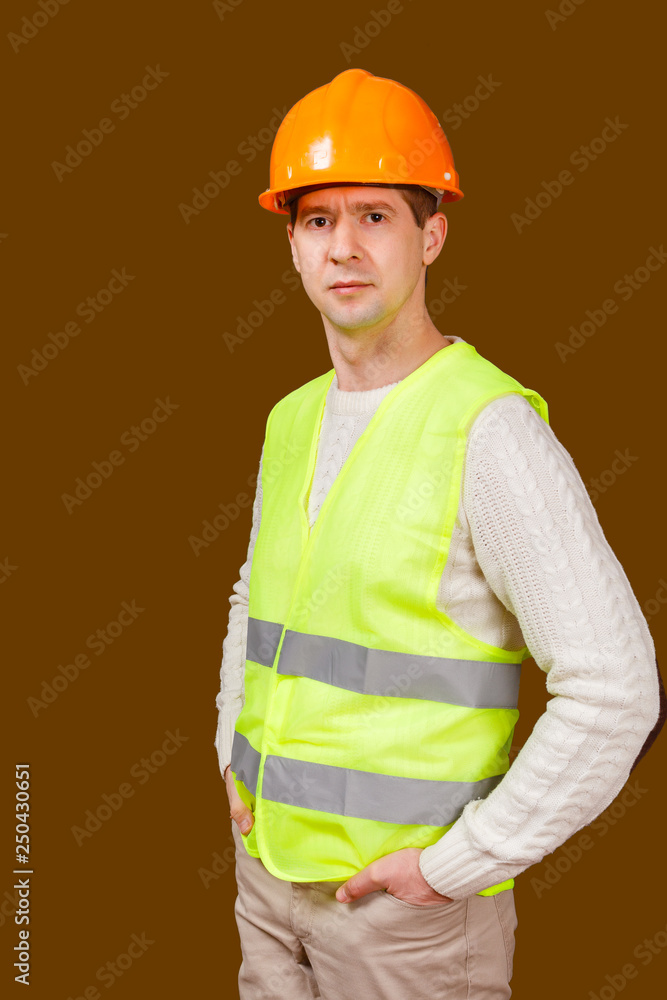 The man in a construction helmet and a vest looks in the camera The man in a construction helmet and a vest looks in the camera