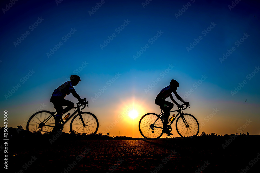 Silhouette of cyclist in sunset background.