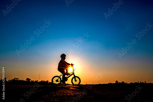 Silhouette of cyclist in sunset background. © patanasak