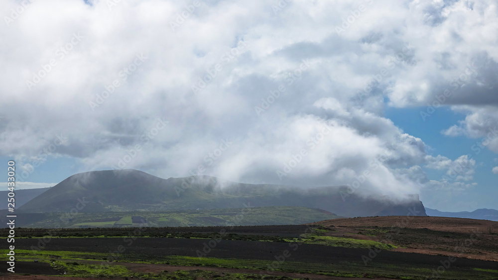 Clouds, fog and rain over a green volcanic mountain on Lanzarote.