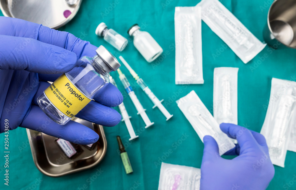 Nurse preparing hospital medication, Left hand holding propofol vial, conceptual image, horizontal composition