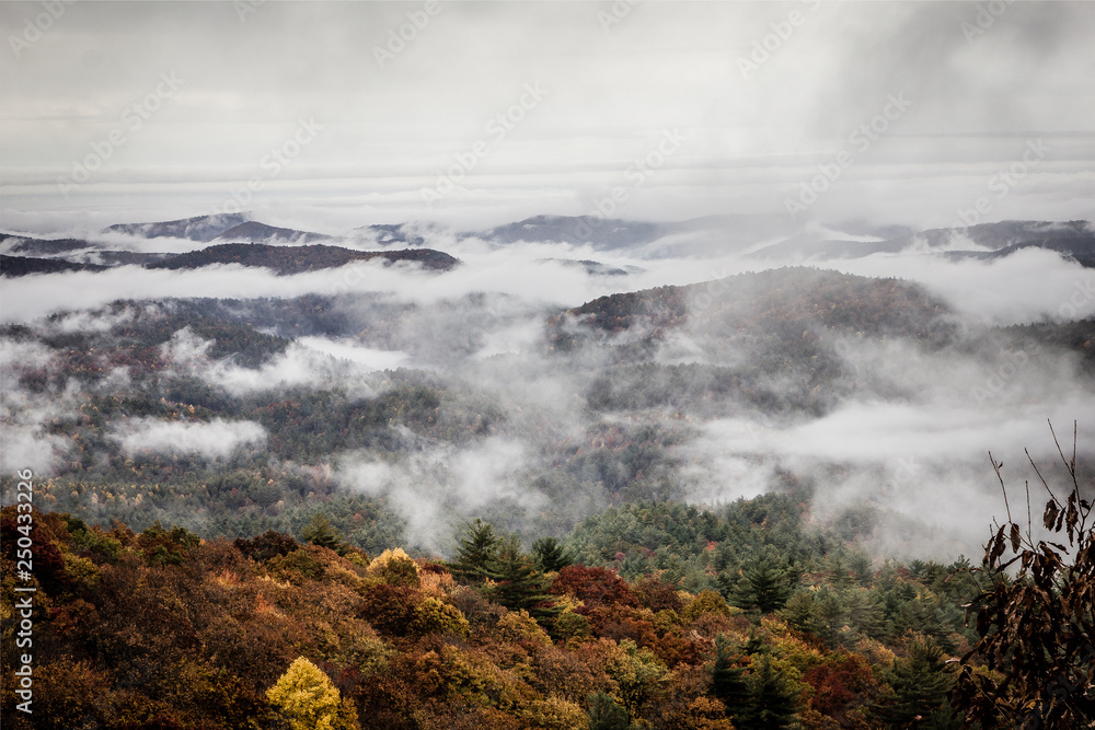 Stratus clouds rolling in over mountainous region with fall colors