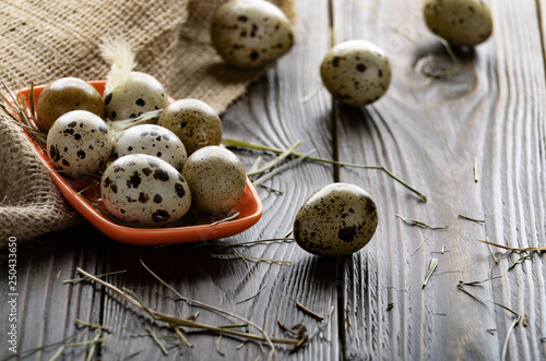 Fresh organic quail eggs in orange clay plate on wooden rustic kitchen table. Space for text