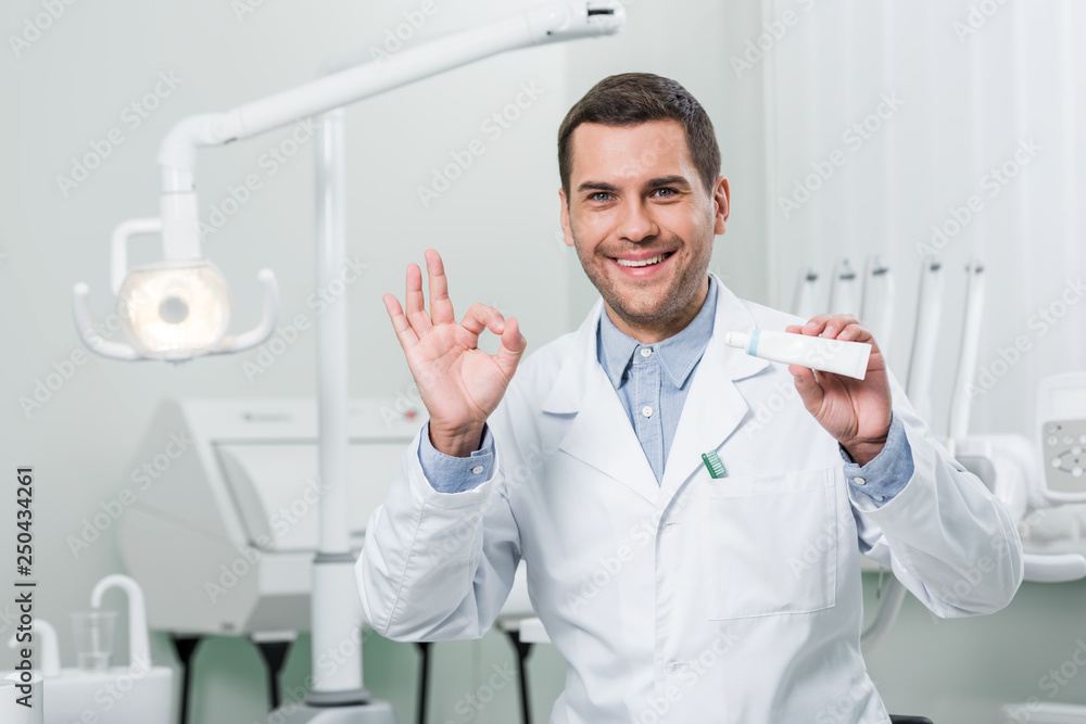 dentist holding toothpaste and showing ok sign in dental clinic Stock