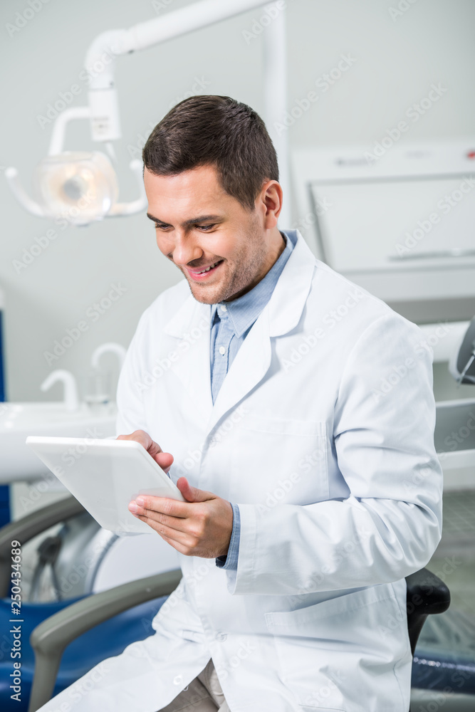cheerful dentist in white coat holding digital tablet in dental clinic cheerful dentist in white coat holding digital tablet in dental clinic