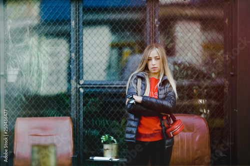 Streetstyle female portrait. Blonde woman in leather jacket poses on the street outside