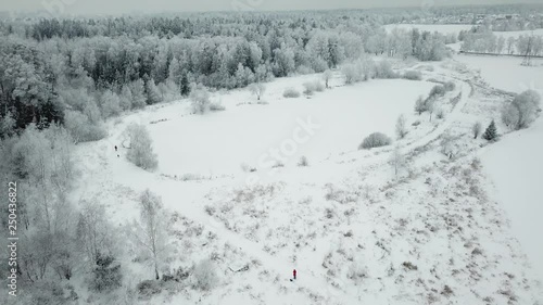 Flying over small pond on the river Razderiha near winter forest. Aerial view landscape. photo