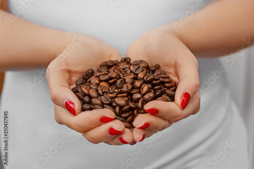 Handful of fresh organic coffee beans. Food and drink coffee background. Coffee beans in young girl hands