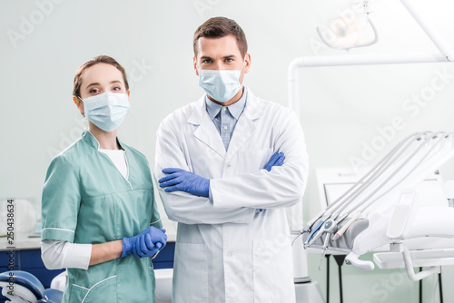 dentists in masks standing with crossed arms in dental clinic photo