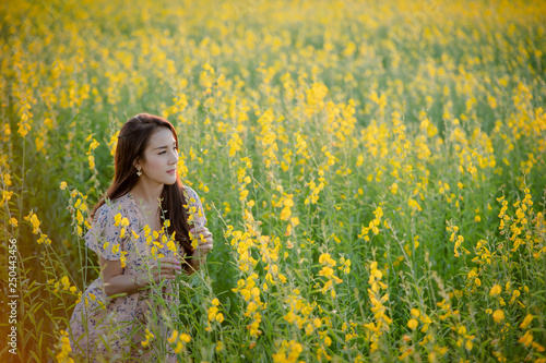 Portrait of happy beautiful happy young woman relaxing in park. Woman in a yellow flower garden. © visoot