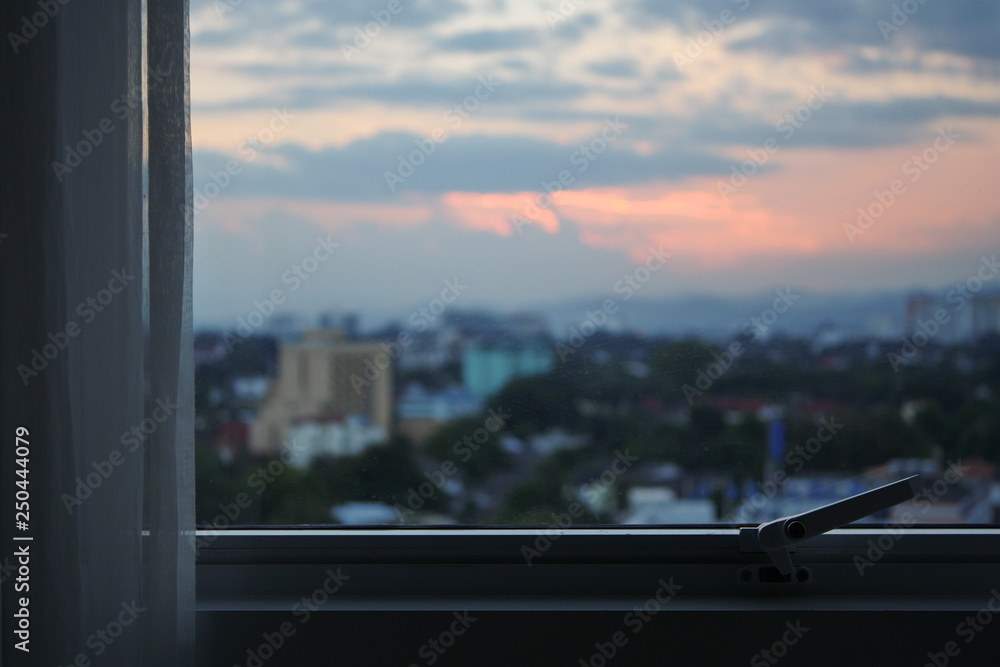 Naklejka premium glass window with sunset sky in the city view outside the room