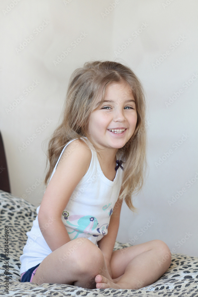 Cute little baby girl woke up early on a sunny morning and sits on a