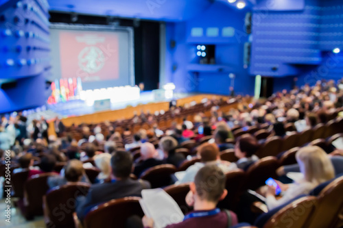Defocused image. People in the auditorium. International conference. Flags of different countries on stage. photo