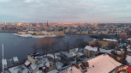 Winter in Stockholm, Sweden aerial view. Drone shot flying up over apartment buildings and showing the beautiful capital city of Sweden. Snowy buildings, Riddarholmen island and ferry boat
