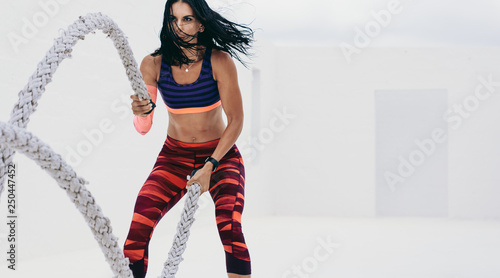 Fitness woman doing workout using battle ropes