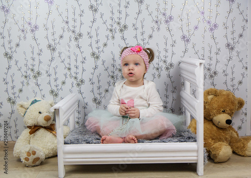 The baby is sitting in the crib and smiling.