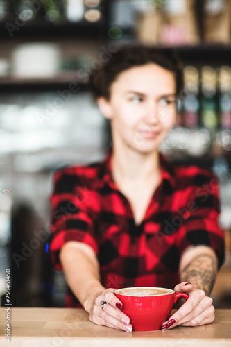 Cropped view of pretty barista holding cup of coffee at the counter in coffee shop